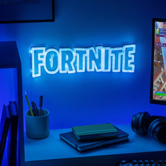 Neon 'Fortnite' sign on a desk with gaming equipment
